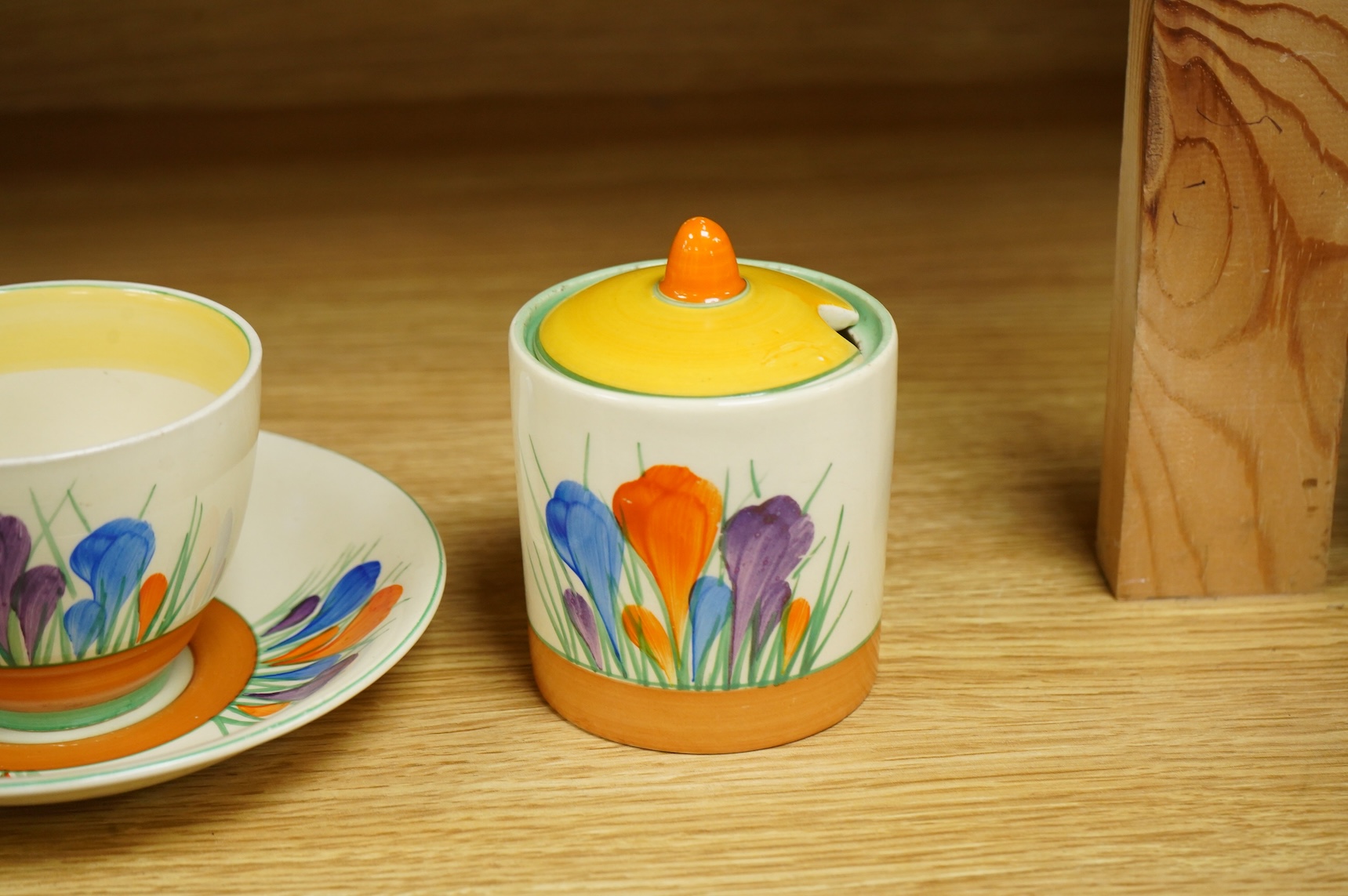 A Clarice Cliff ‘crocus’ pattern preserve jar and cover, 10cm high and a similar cup and saucer